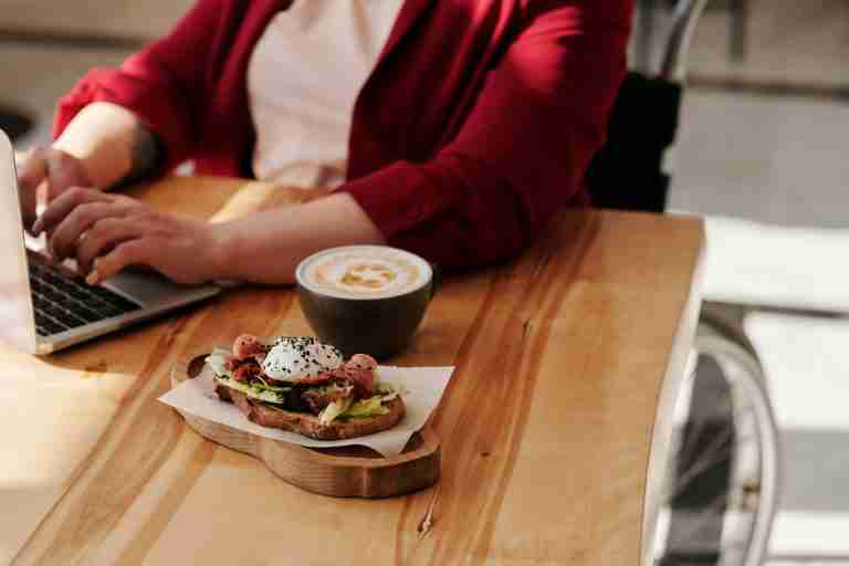 woman on laptop with lunch next to her