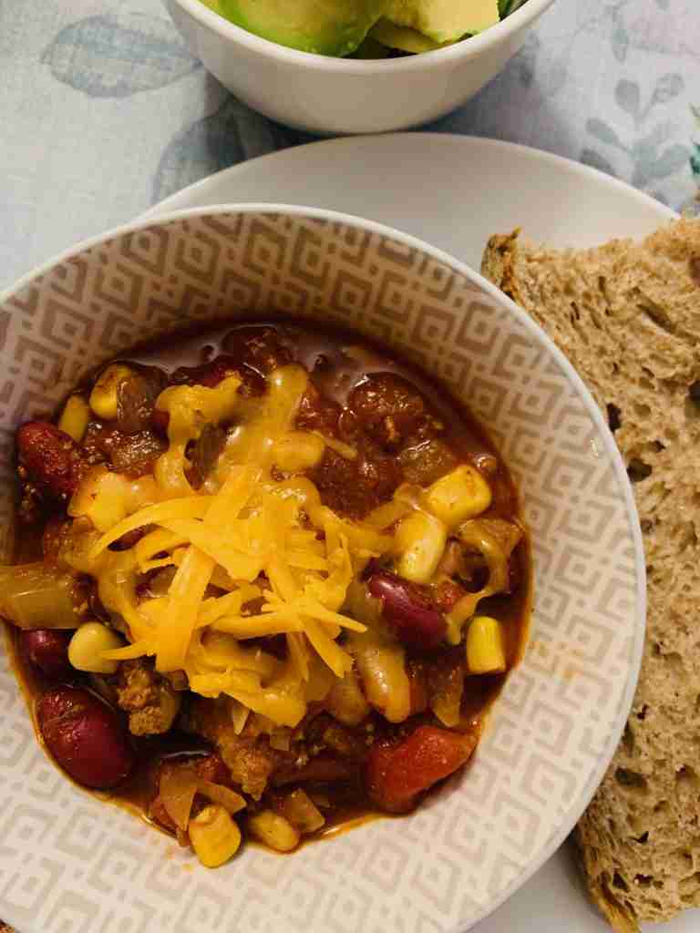 A cup of chili topped with shredded cheese